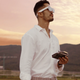 Man wearing AR glasses stares thoughtfully into the sunset holding a remote control, likely wondering where his drone went.
